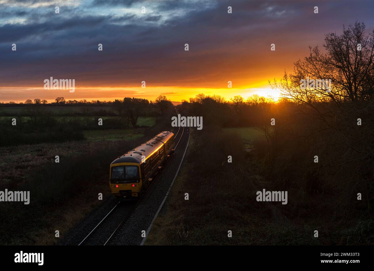 Primo treno Great Western Turbo 165120 a Burleigh sulla linea ferroviaria Cotswolds a binario singolo con il sole nascente Foto Stock