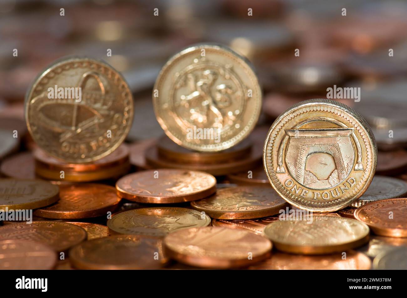 Scatto in studio di monete da tre sterline in valuta Sterling in piedi sul tavolo con monete sfocate sullo sfondo Foto Stock