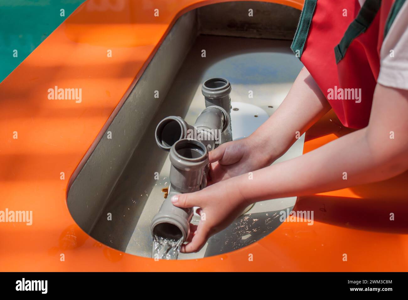 Bambini che giocano con i tubi dell'acqua ed esplorano ciò che è l'impianto idraulico nel museo per bambini, attenzione selettiva Foto Stock