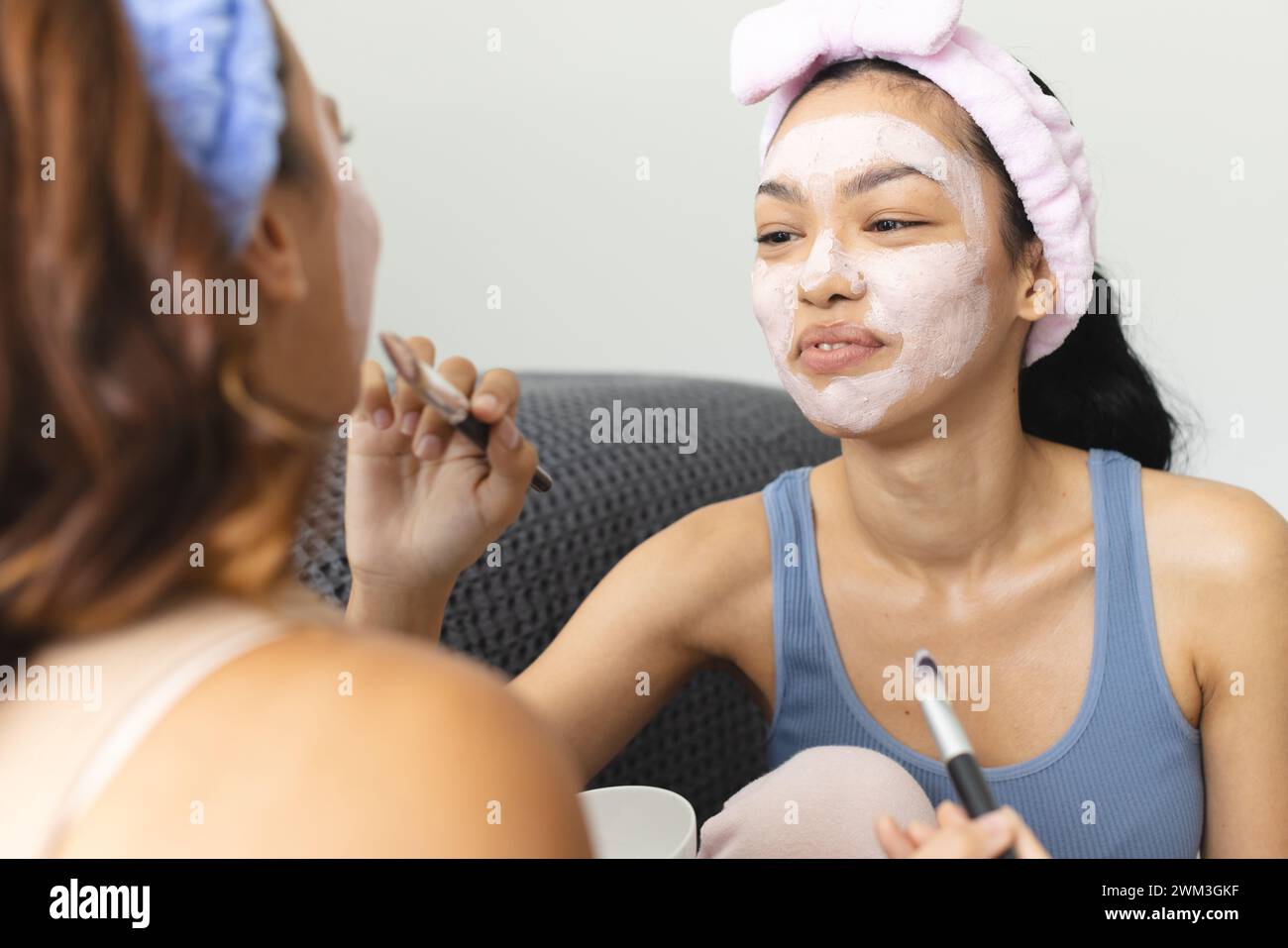 Due giovani donne birazziali si impegnano in una routine di cura della pelle a casa Foto Stock