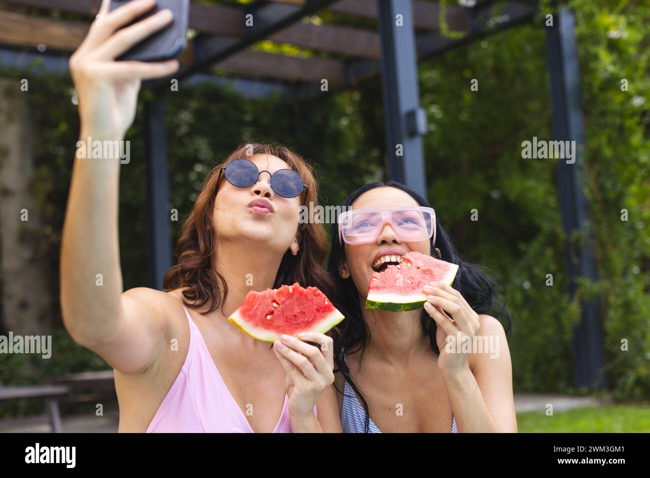 Due giovani donne birazziali si godono una giornata di sole all'aperto, scattando un selfie Foto Stock
