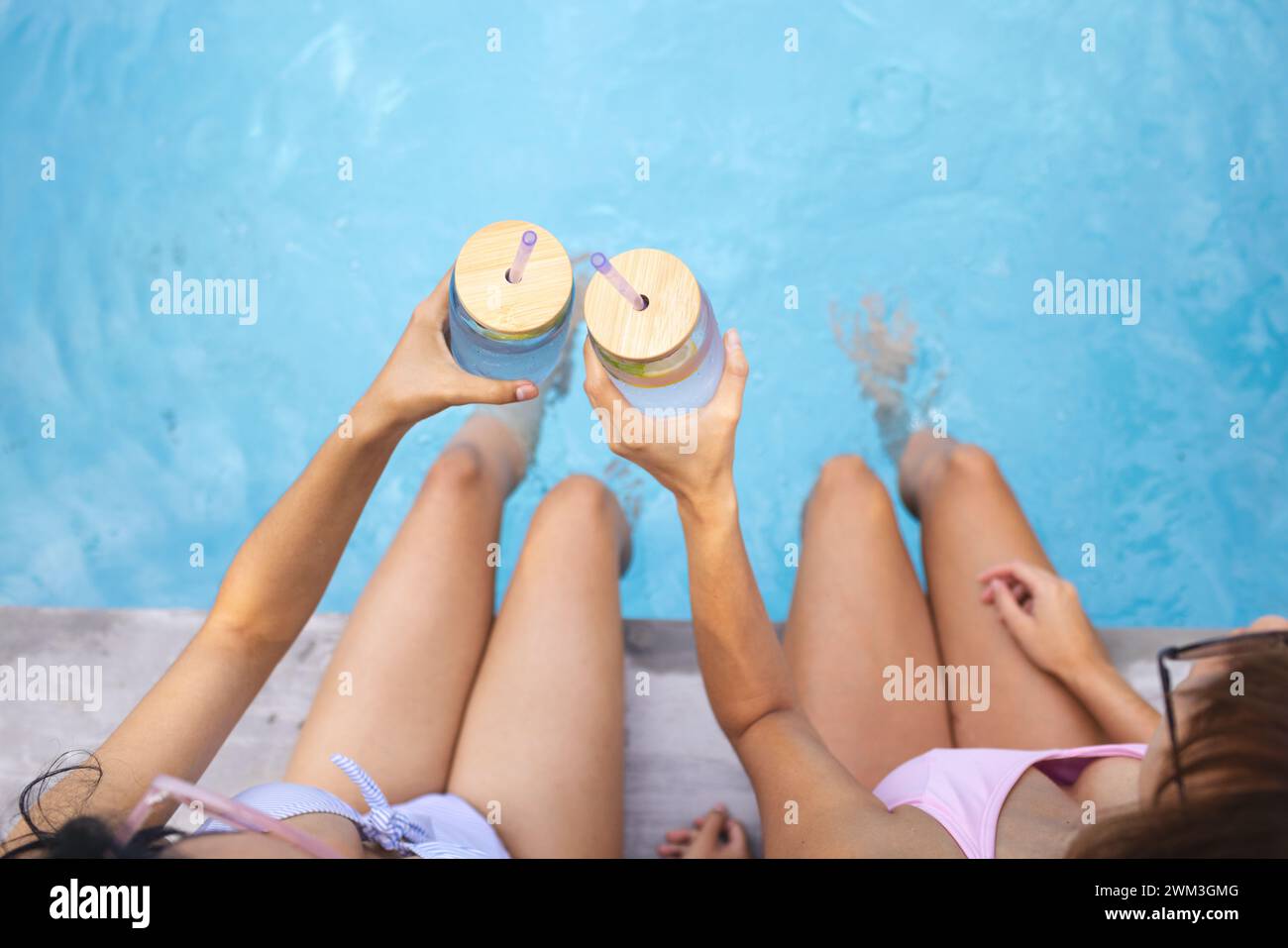 Due amici si godono bevande rinfrescanti a bordo piscina, con spazio per fotocopie Foto Stock