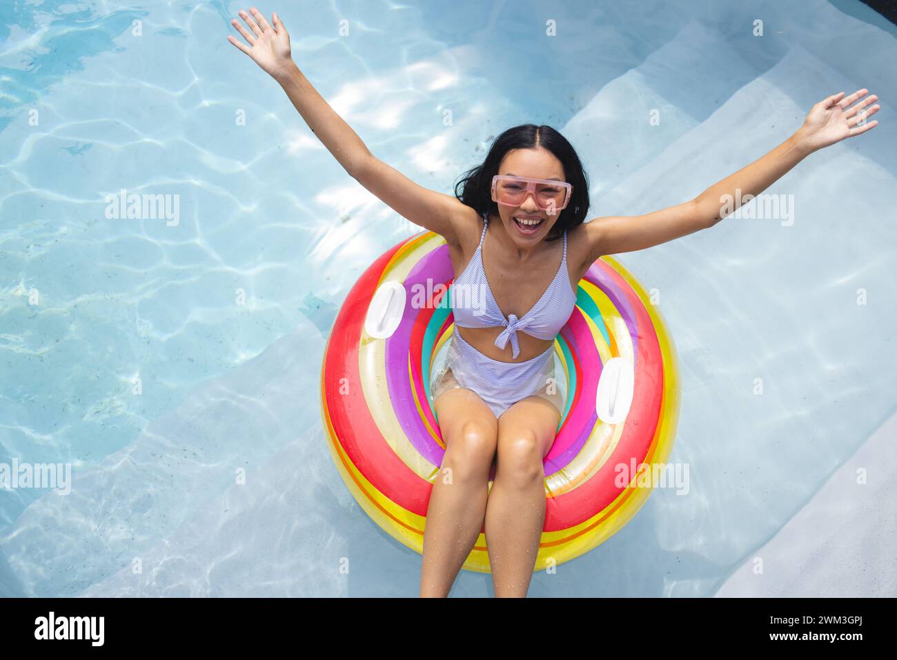 La giovane donna birazziale gode di una giornata di sole in piscina, con spazio per fotocopie Foto Stock