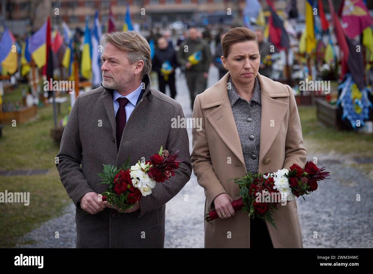 Leopoli, Ucraina. 23 febbraio 2024. Il primo ministro danese mette Frederiksen, a destra, e il marito Bo Tengberg, a sinistra, rendono omaggio ai soldati caduti sul campo di Marte all'interno del cimitero di Lychakiv, 23 febbraio 2024 a Leopoli, Ucraina. Credito: Pool Photo/Ufficio Stampa Presidenziale ucraino/Alamy Live News Foto Stock