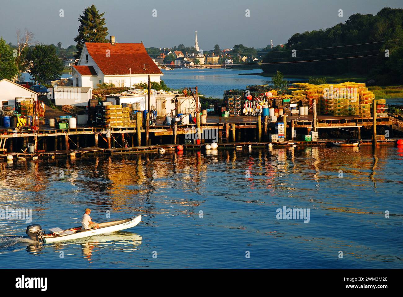 Una piccola barca con un motore fuoribordo supera il molo di pesca pieno di trappole per aragoste a Portsmouth, New Hampshire, sulla costa del New England Foto Stock