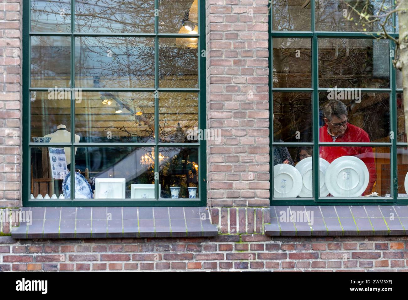 Delft, Paesi Bassi. 23 febbraio 2024. Un uomo vede gli oggetti in porcellana esposti al Royal Delft Museum di Delft, nei Paesi Bassi, il 23 febbraio 2024. Crediti: Meng Dingbo/Xinhua/Alamy Live News Foto Stock