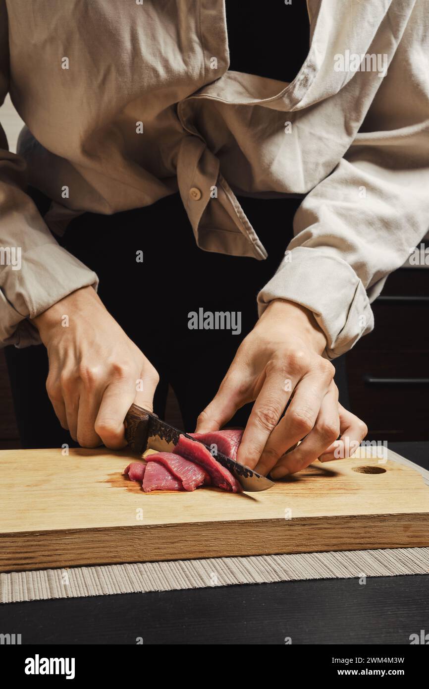 Primo piano delle mani della donna che affetta sottilmente carne di manzo cruda per barbecue coreano Foto Stock
