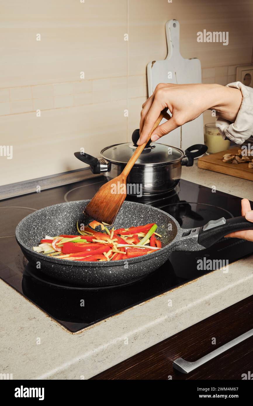Donna irriconoscibile che mescola il condimento per spaghetti di riso con spatola di legno Foto Stock
