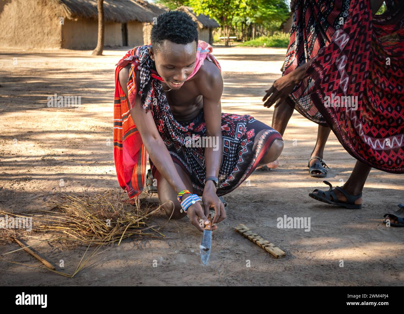 Un guerriero Maasai inizia il fuoco per attrito dopo aver sfregato i bastoni in un villaggio di Mikumi, Tanzania. Foto Stock
