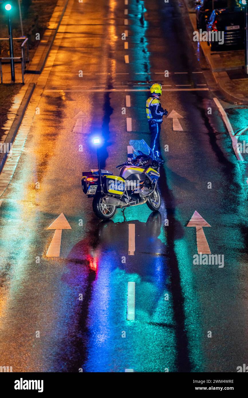 Poliziotto con moto, in caso di pioggia, che blocca una strada, motocicletta della polizia con luce blu, Foto Stock