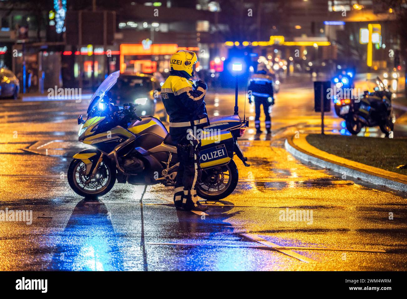 Poliziotto con moto, in caso di pioggia, che blocca una strada, motocicletta della polizia con luce blu, Foto Stock