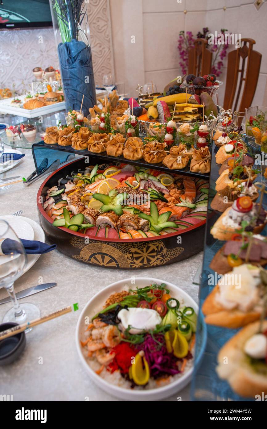 Un sontuoso buffet che offre un ricco assortimento di pesce fresco, sushi, insalate, frutta e pasticcini, splendidamente disposto su un tavolo bianco immacolato Foto Stock