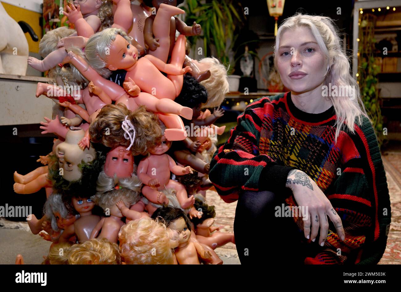 Monaco, Germania. 23 febbraio 2024. L'artista Liza Mercedes siede accanto a una delle sue sculture nel suo studio. Nella sua esplorazione artistica, Mercedes cattura il "tema bambino interiore". Crediti: Felix Hörhager//dpa/Alamy Live News Foto Stock