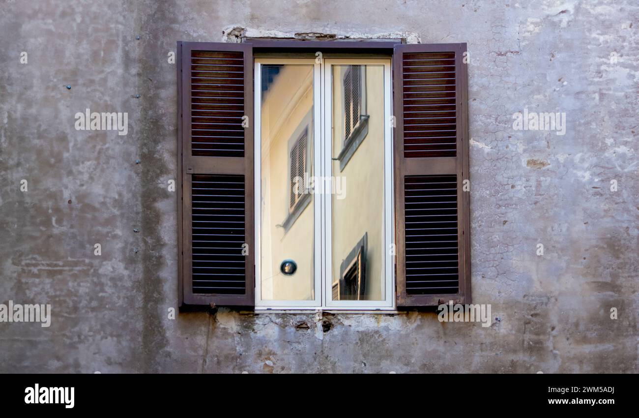 Le finestre con le intemperie riflettono il decadimento urbano di un paesaggio urbano italiano, trasudando fascino vintage Foto Stock