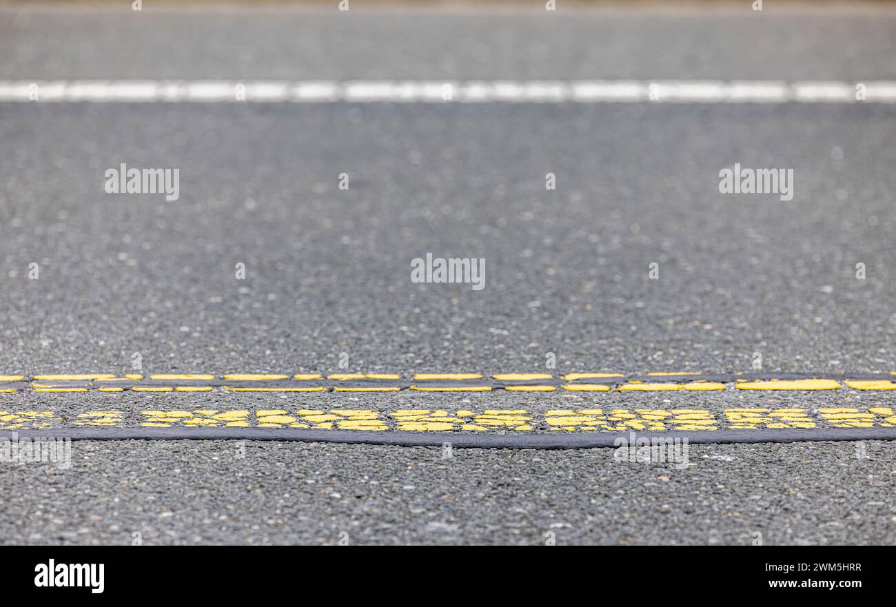 Immagine dettagliata di una carreggiata e di una doppia linea gialla Foto Stock