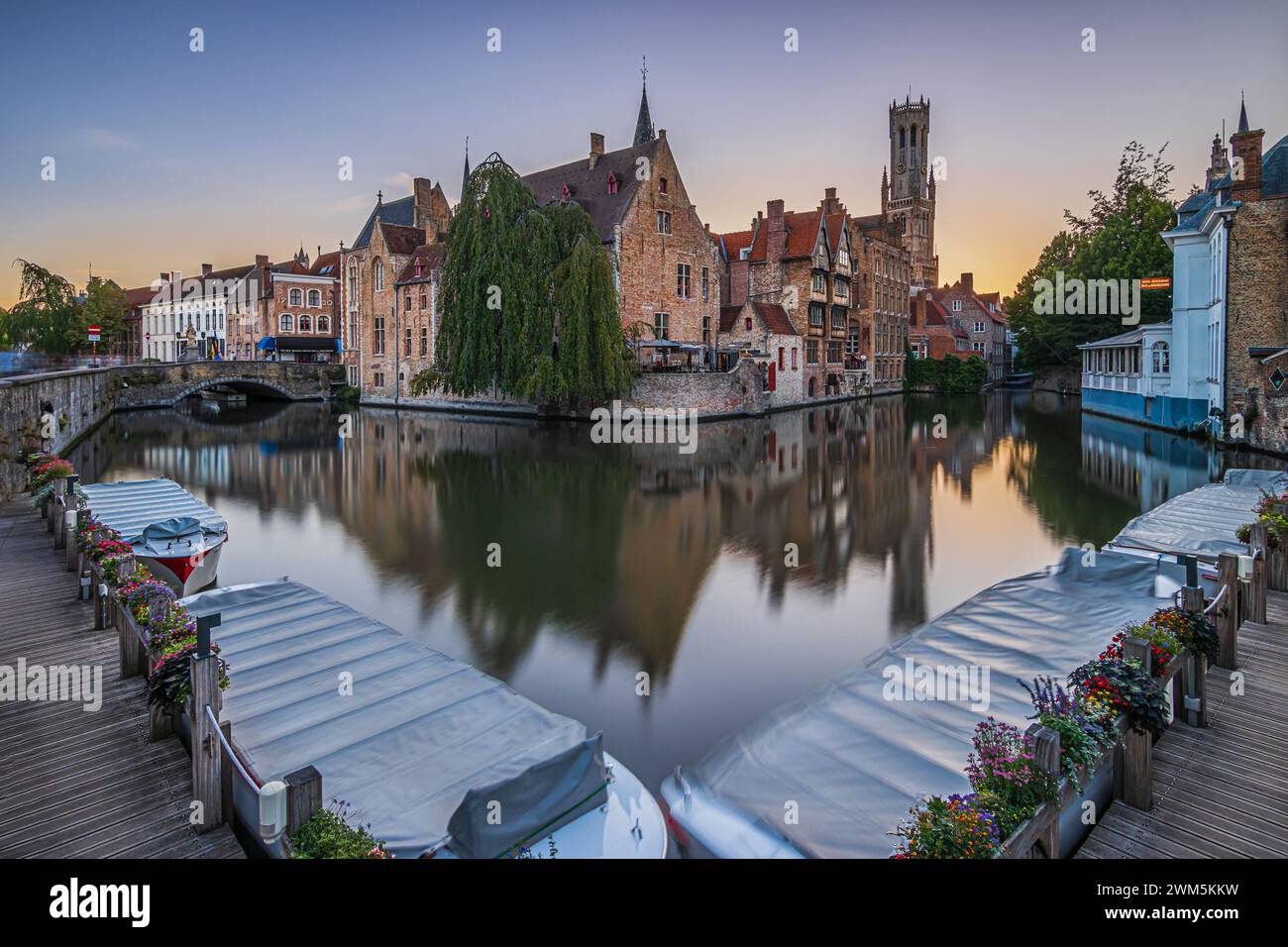 Tramonto sul canale di Rosary Quay nella città vecchia di Bruges con barche al molo. Storiche case mercantili e case per metà in legno con riflessi Foto Stock Tramonto sul canale di Rosary Quay nella città vecchia di Bruges con barche al molo. Storiche case mercantili e case per metà in legno con riflessi Foto Stock