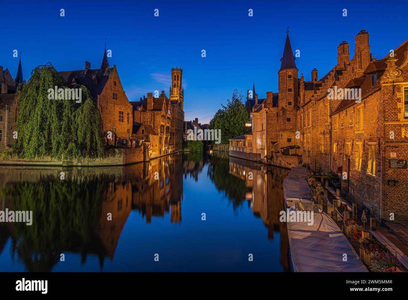 Bruges la sera all'ora blu. Il canale di Rosary Quay nel centro della città anseatica. Edifici illuminati e campanile della città vecchia. Foto Stock Bruges la sera all'ora blu. Il canale di Rosary Quay nel centro della città anseatica. Edifici illuminati e campanile della città vecchia. Foto Stock