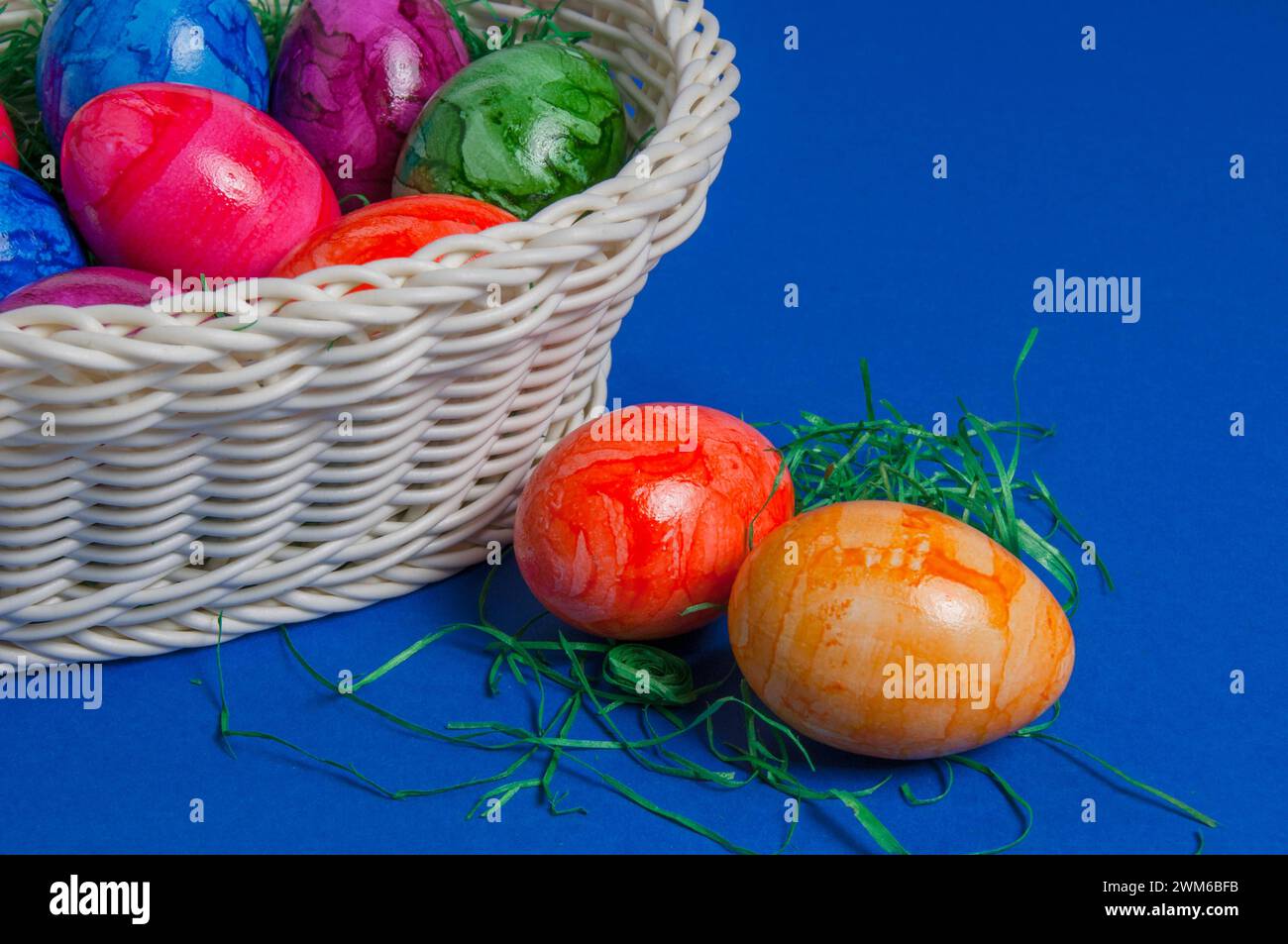 Ein Korb mit bunten Ostereiern vor blauem Hintergrund *** Un cestino di uova di Pasqua colorate su sfondo blu Foto Stock