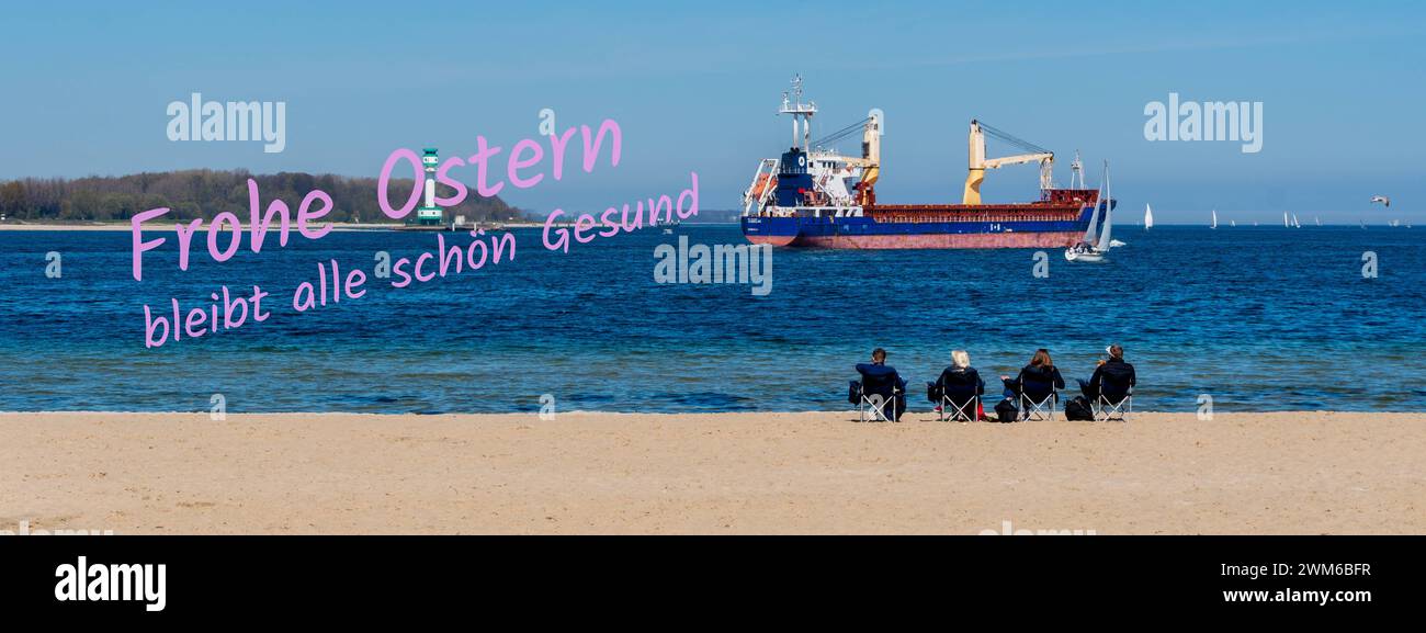 Panoramaufnahme Frohe Ostern bleibt alle schön gesund an einem Strand vier Personen sitzend im Hintergrund passiert ein Frachtschiff *** foto panoramica buona Pasqua tutti in salute su una spiaggia quattro persone sedute sullo sfondo passa una nave da carico Foto Stock