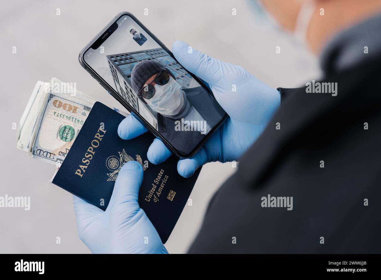 Un uomo con equipaggiamento protettivo ha un passaporto e un telefono, riflettendo le condizioni di viaggio pandemiche. Foto Stock