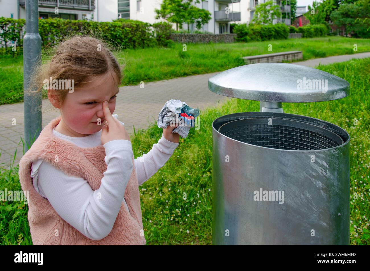 Una ragazza getta la spazzatura in un bidone della spazzatura. Foto Stock