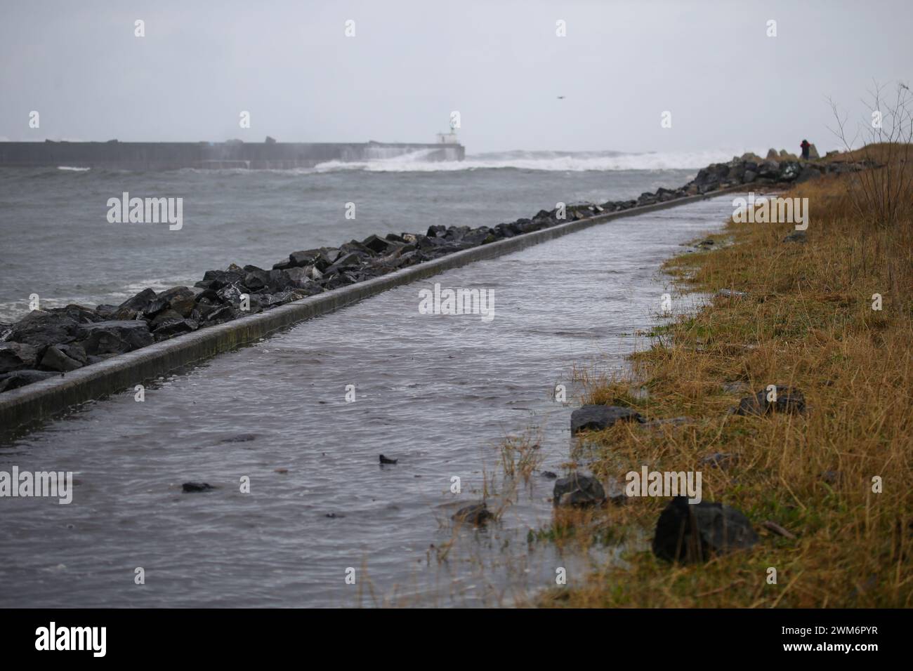 San Juan de la Arena, Spagna, 24 febbraio 2024: L'acqua trabocca il canale e inonda i marciapiedi durante l'allarme arancione per onde nel Mar Cantabrico a causa della tempesta Louis, il 24 febbraio 2024, a San Juan de Arena, Spagna. Crediti: Alberto Brevers / Alamy Live News. Foto Stock