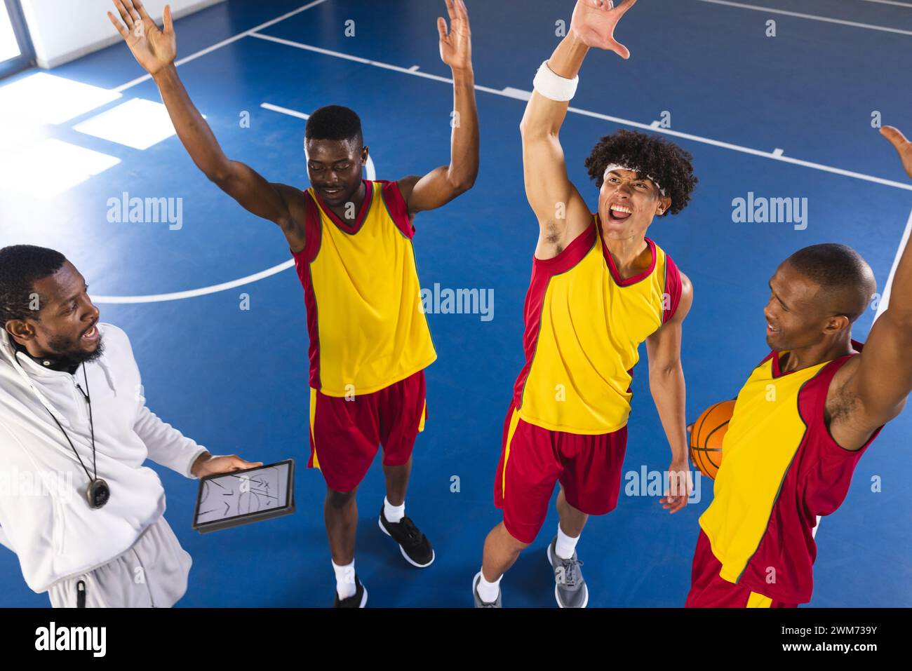 Gli allenatori e i giocatori di basket celebrano un gioco di successo al chiuso Foto Stock