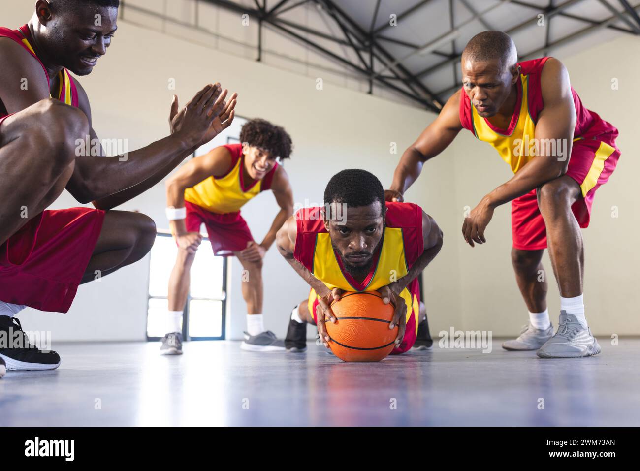 Gli uomini afroamericani e birazziali giocano a basket al chiuso Foto Stock