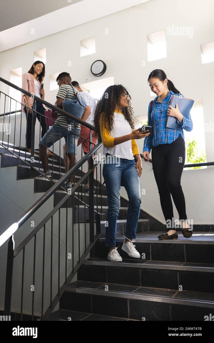 Diversi adolescenti chiacchierano in una scala delle superiori Foto Stock