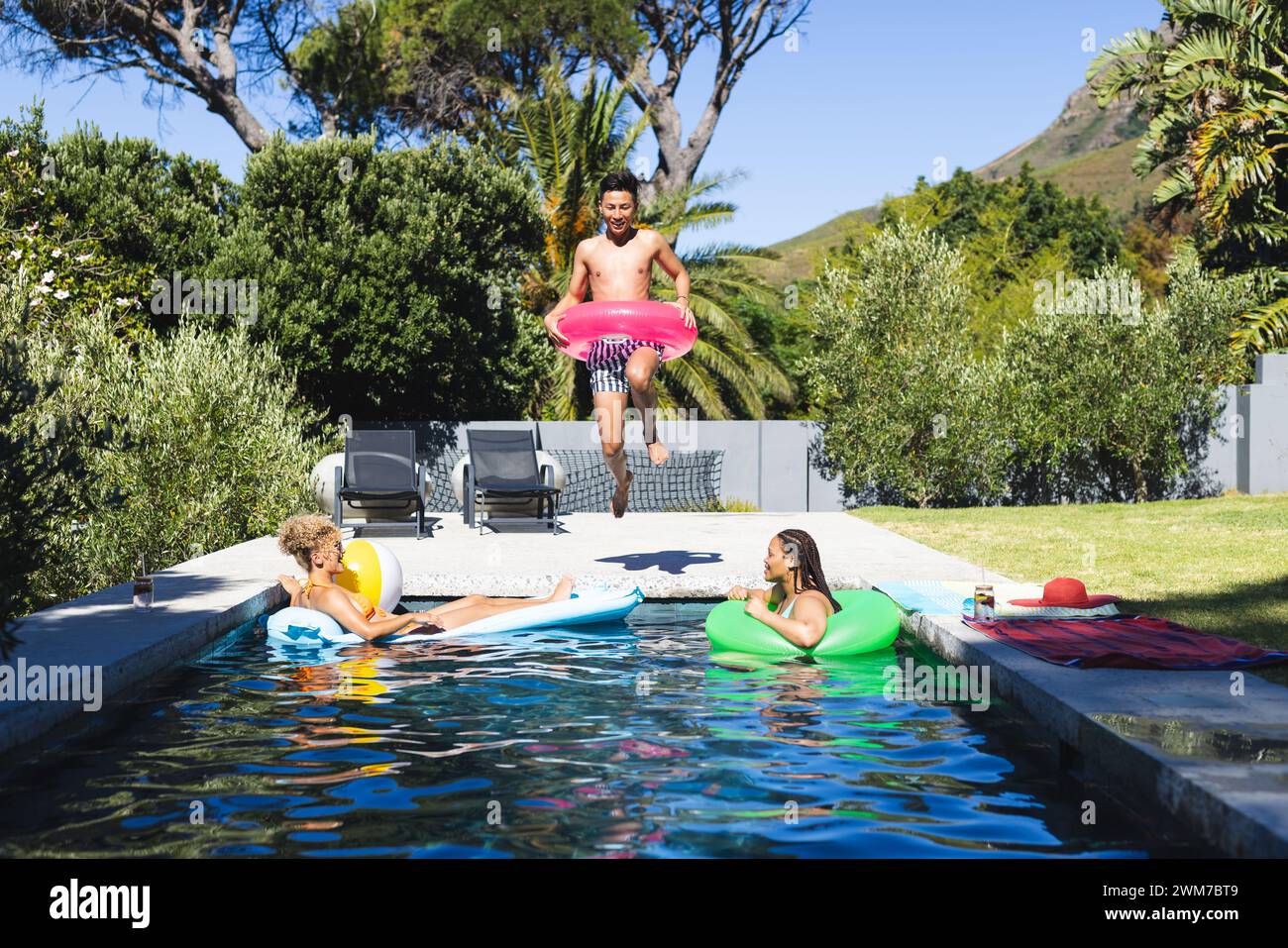 Gli amici trascorrono una giornata di sole in una piscina di casa, con spazio fotocopie Foto Stock