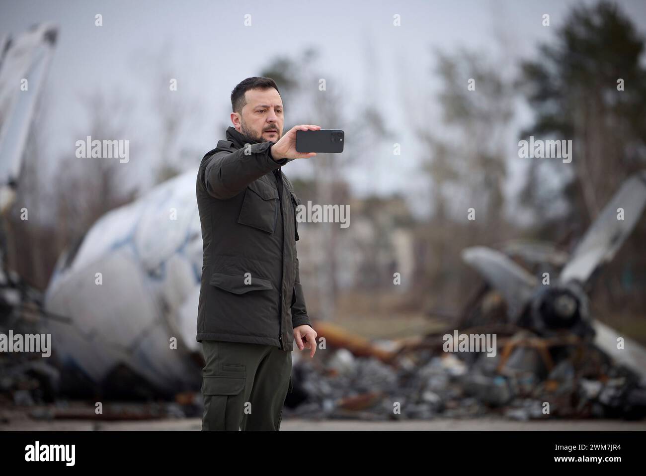 Kiev, Ucraina. 24 febbraio 2024. Il presidente ucraino Volodymyr Zelenskyy consegna video di fronte agli aerei distrutti durante l'invasione russa nel secondo anniversario dell'invasione all'aeroporto di Hostomel, 24 febbraio 2024 a Kiev, Ucraina. Credito: Pool Photo/Ufficio Stampa Presidenziale ucraino/Alamy Live News Foto Stock