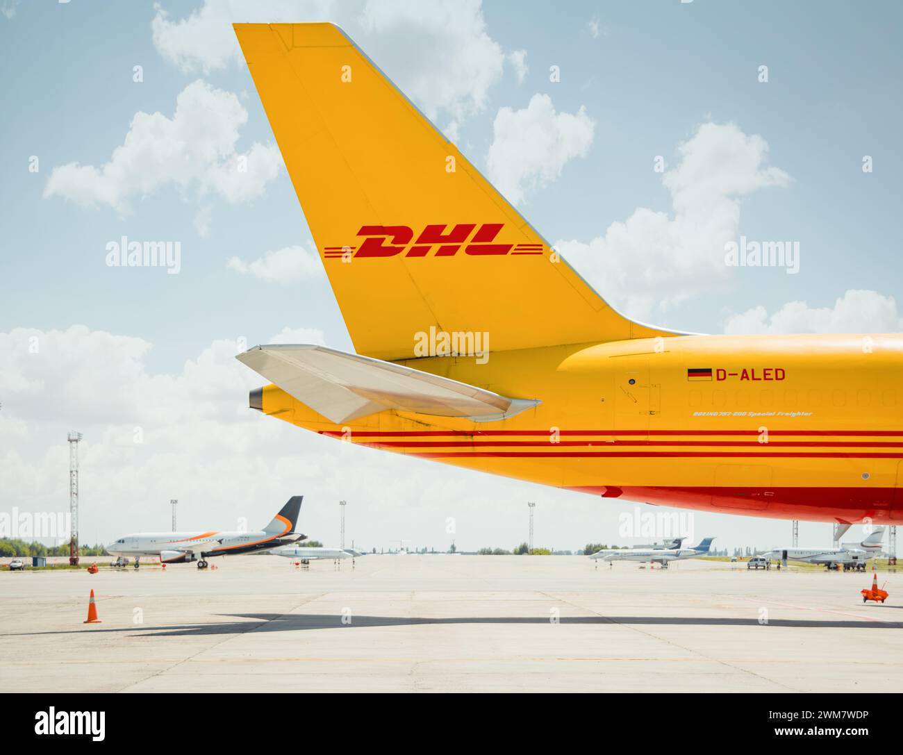 Coda di un aeromobile cargo DHL. Vista laterale dell'impennaggio del Boeing 757 (D-ALED) parcheggiato sul grembiule in una giornata di sole. Foto Stock