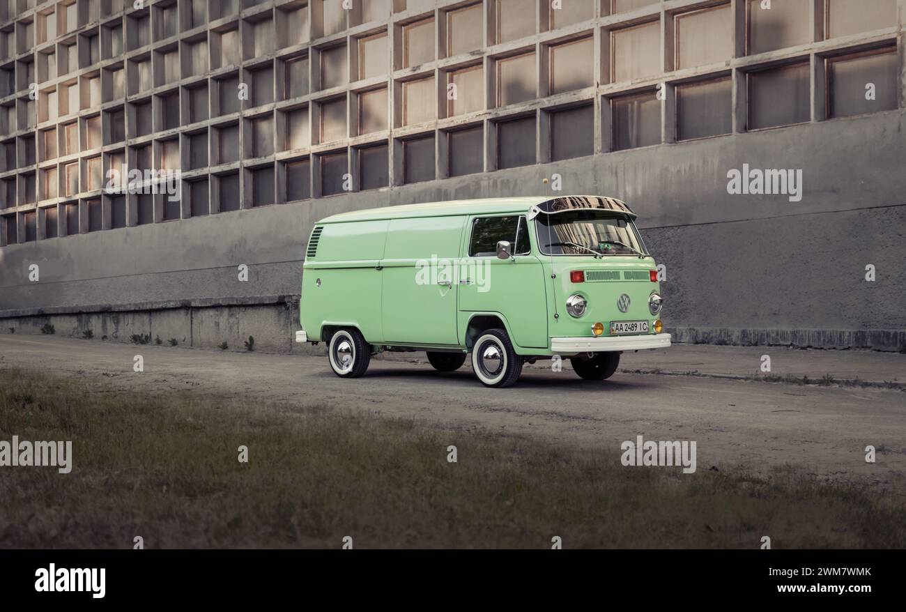 Classico autobus verde Volkswagen Transporter parcheggiato di fronte a una parete di cemento, vista prospettica. Foto Stock