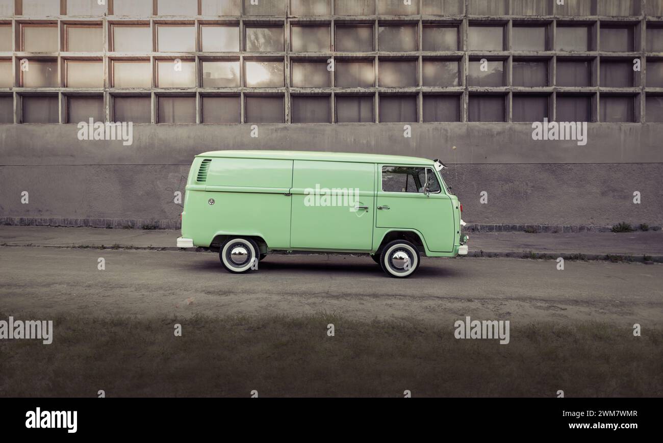 Autobus Volkswagen Transporter classico verde parcheggiato davanti a una parete in cemento, vista profilo laterale. Foto Stock