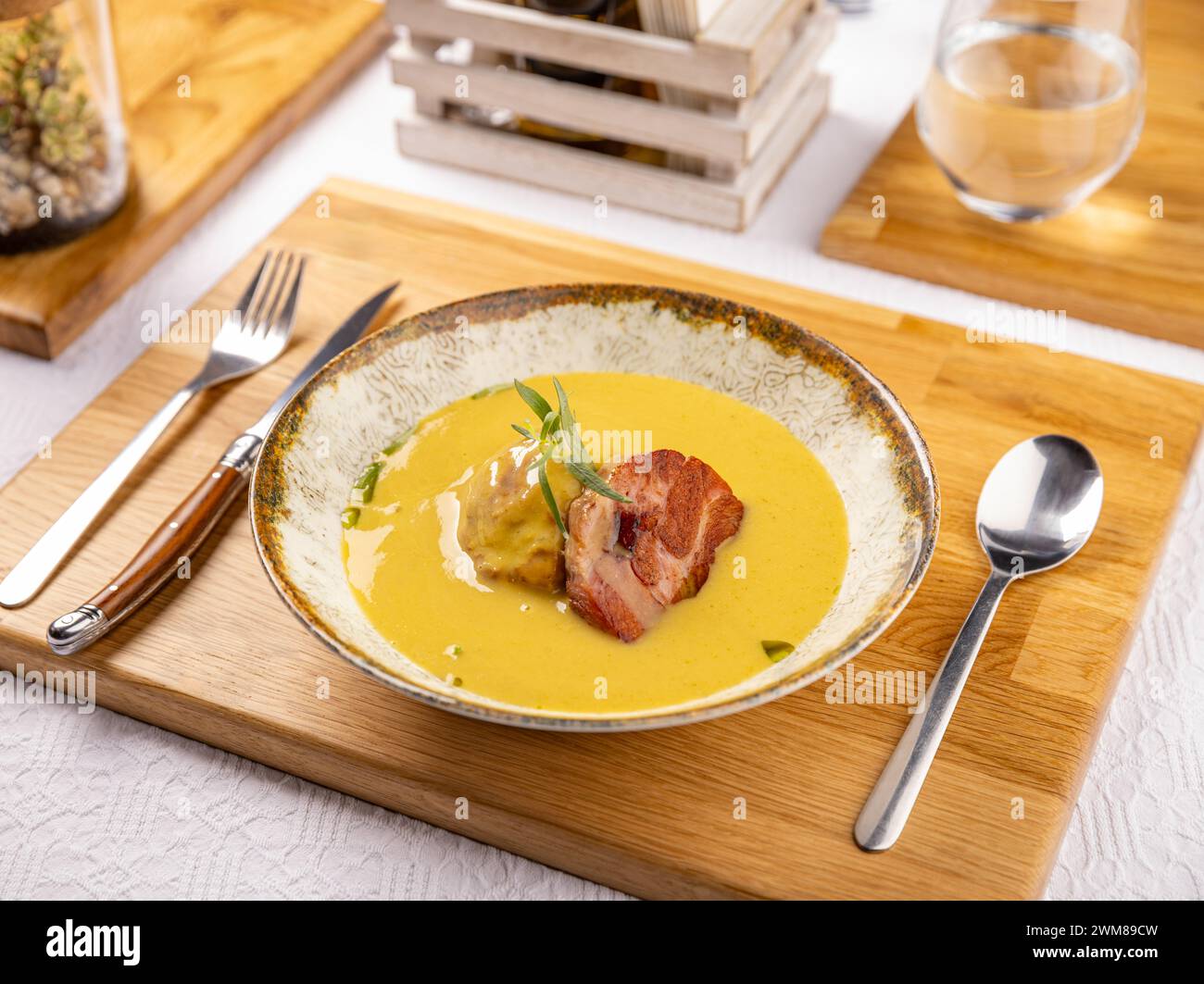 Zuppa di patate in stile moderno con patate al forno e prosciutto affumicato su un elegante tavolo del ristorante Foto Stock