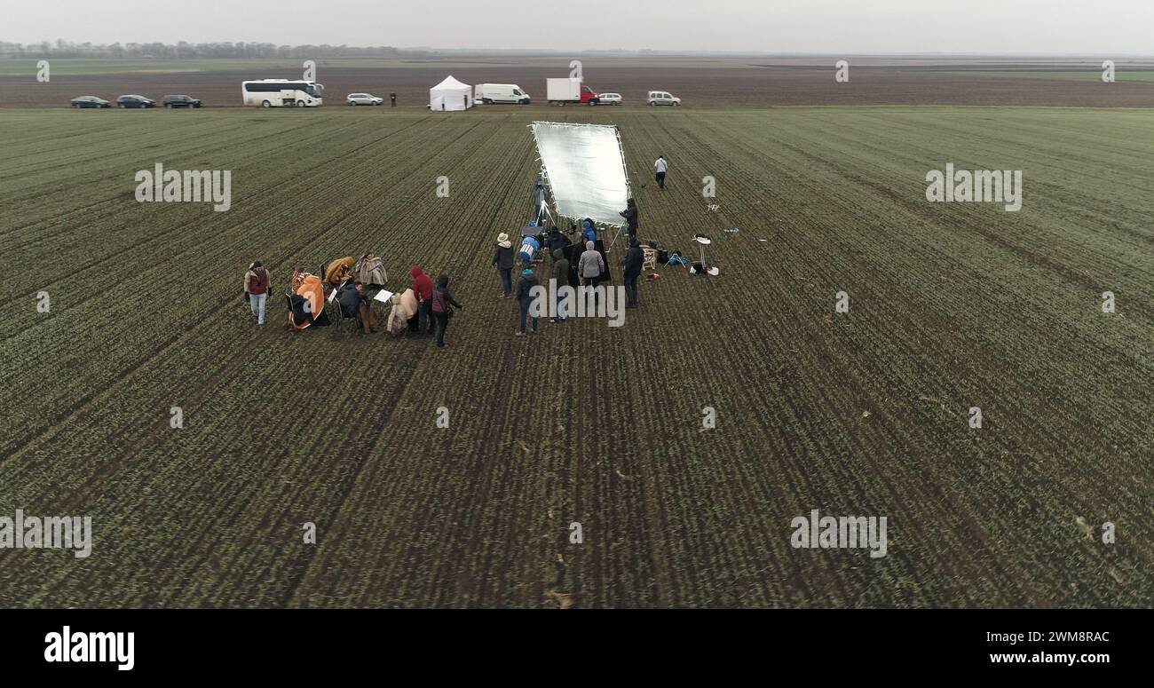 La troupe cinematografica prepara una scena nel campo di ritaglio. Fumoso colpo aereo invernale. Foto Stock