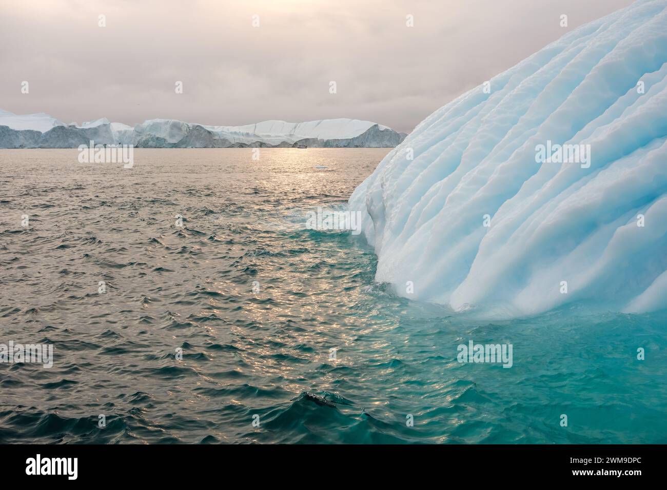 Il bellissimo iceberg rigato rivela linee di turchese circondate da acque verdi. Icefjord, Illulisat, Groenlandia. Foto Stock
