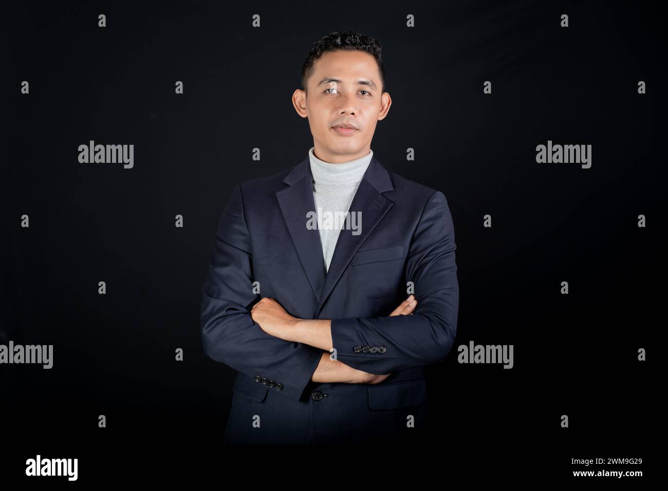 Ritratto di un bell'uomo elegante in tuta nera su sfondo nero. Modalità Studio verticale Foto Stock