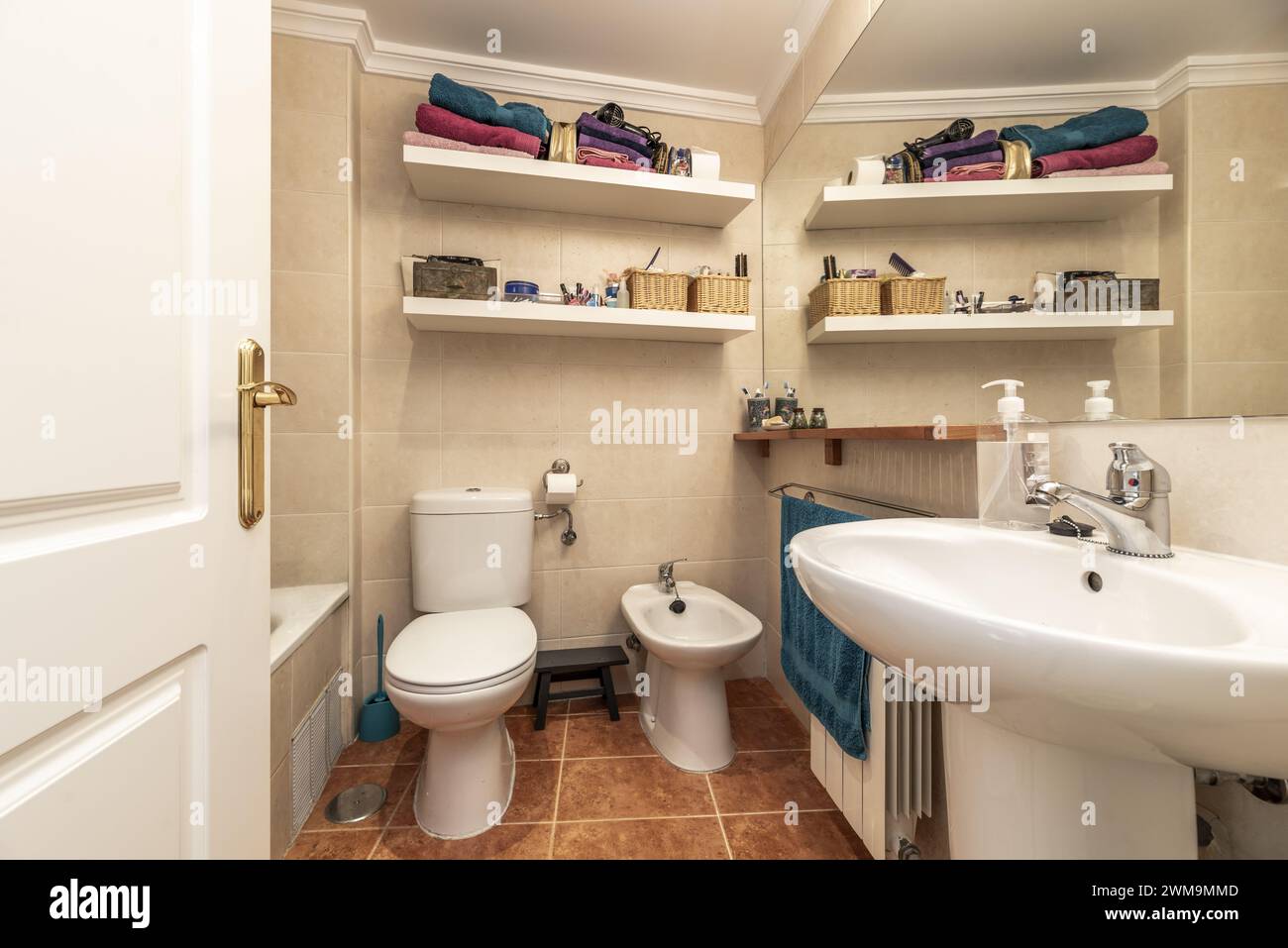 Bagno con piccolo lavandino in porcellana con piedistallo coordinato, ripiani bianchi sulla parete e specchio integrato nella parete Foto Stock