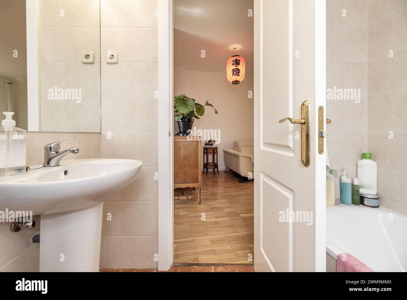 Bagno con piccolo lavandino in porcellana con piedistallo dello stesso materiale e porte in legno bianco Foto Stock