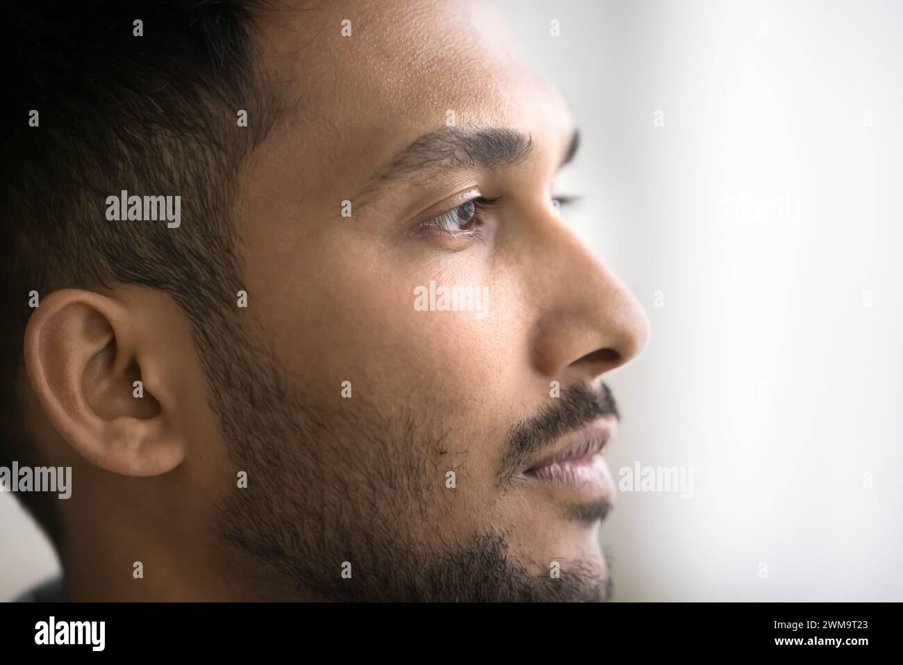 Immagine ravvicinata di un giovane indiano pensivo che guarda in lontananza Foto Stock