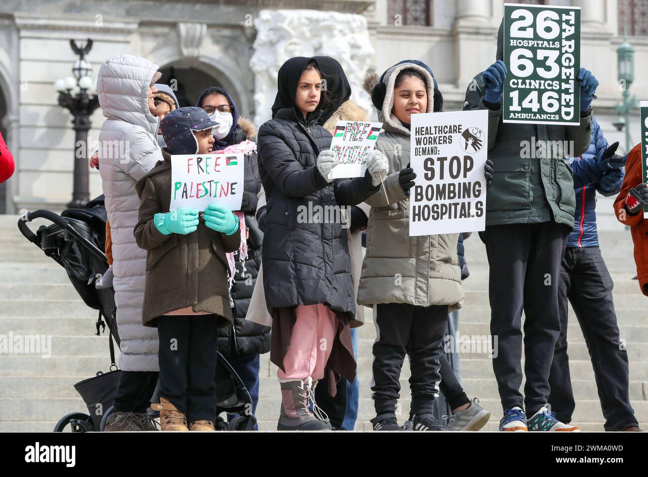 Harrisburg, Stati Uniti. 24 febbraio 2024. I bambini tengono dei cartelli durante il rally dei lavoratori sanitari per la Palestina presso il Campidoglio dello Stato della Pennsylvania. La Coalizione palestinese di Harrisburg insieme ad altre organizzazioni tra cui la Coalizione palestinese di Pittsburgh, la Penn State Students for Justice in Palestine e la Jewish Voice for Peace Philadelphia organizzarono la manifestazione per mostrare solidarietà agli operatori sanitari di Gaza e per chiedere un cessate il fuoco immediato. Credito: SOPA Images Limited/Alamy Live News Foto Stock