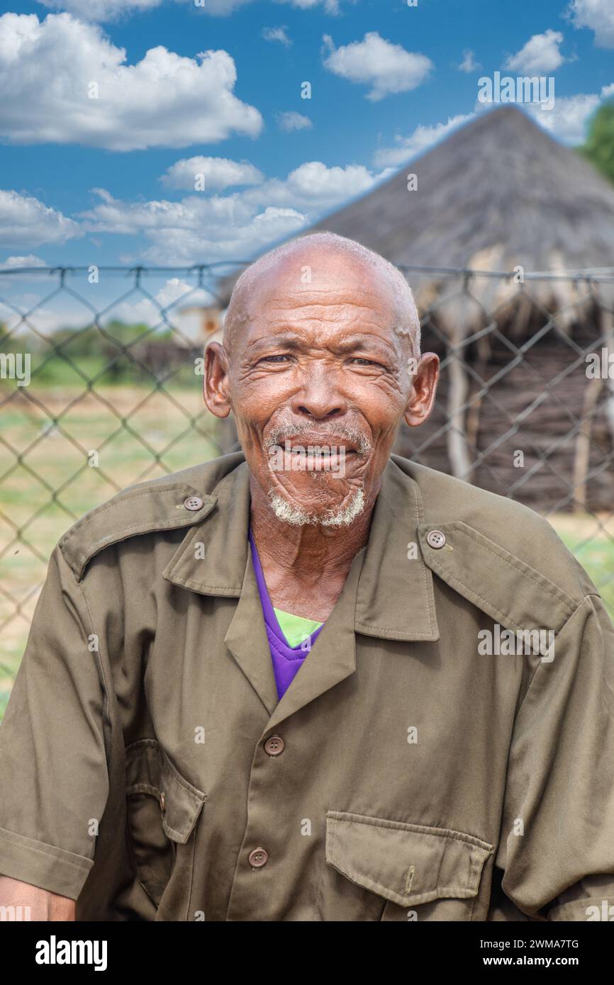 felice vecchio villaggio africano uomo in piedi nel cortile, nella capanna sullo sfondo con tetto di paglia e cielo blu, sud africa Foto Stock