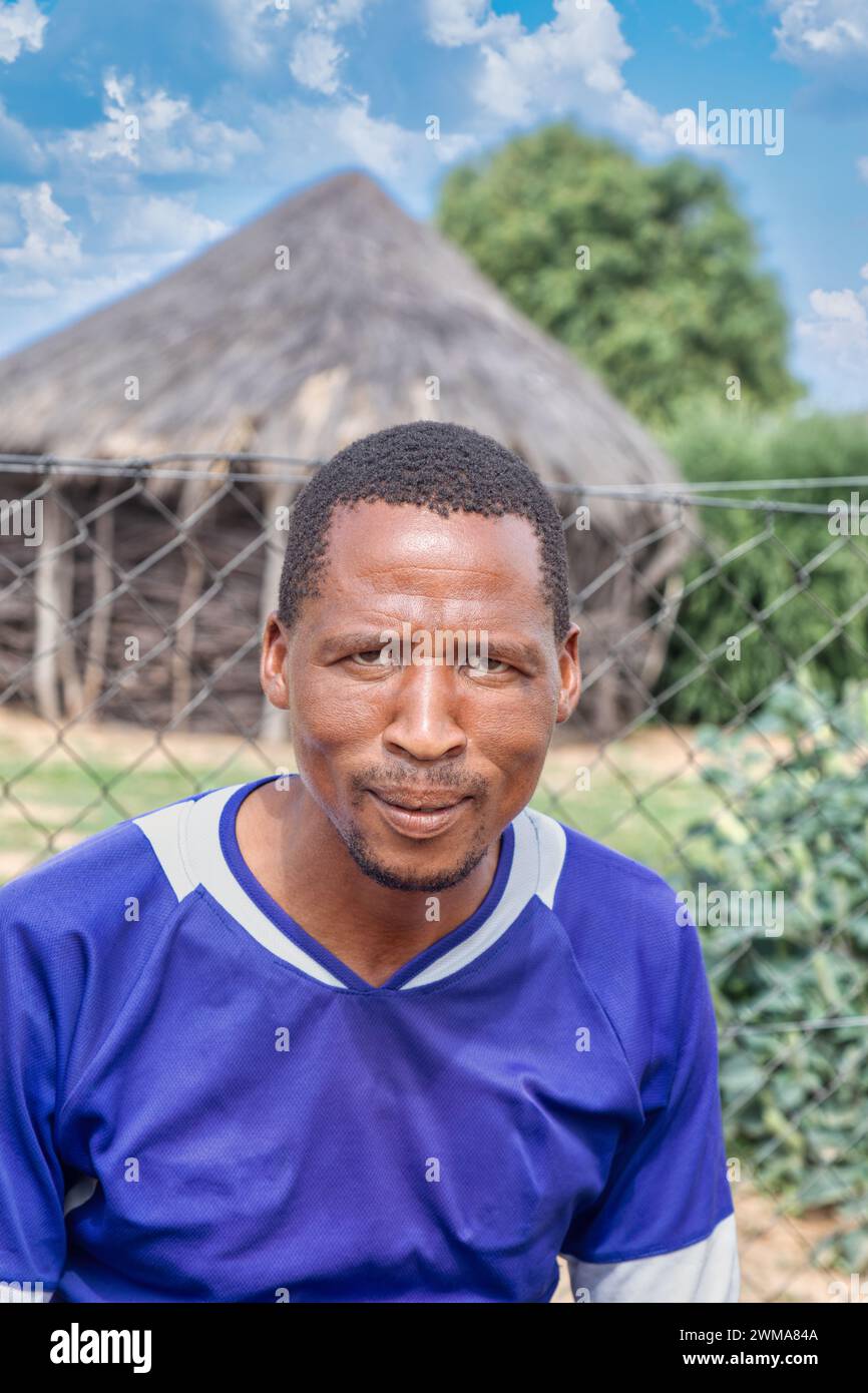 villaggio africano uomo nel cortile, sullo sfondo capanna con tetto di paglia e cielo blu, sud africa Foto Stock