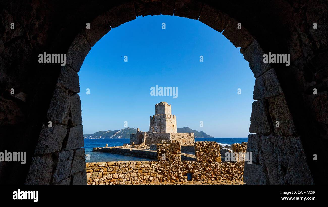 Vista da un arco su un'antica guglia da torre di avvistamento in pietra di fronte a un pittoresco panorama sul mare, torre medievale ottagonale. Isolotto di Bourtzi, fortezza marina Foto Stock