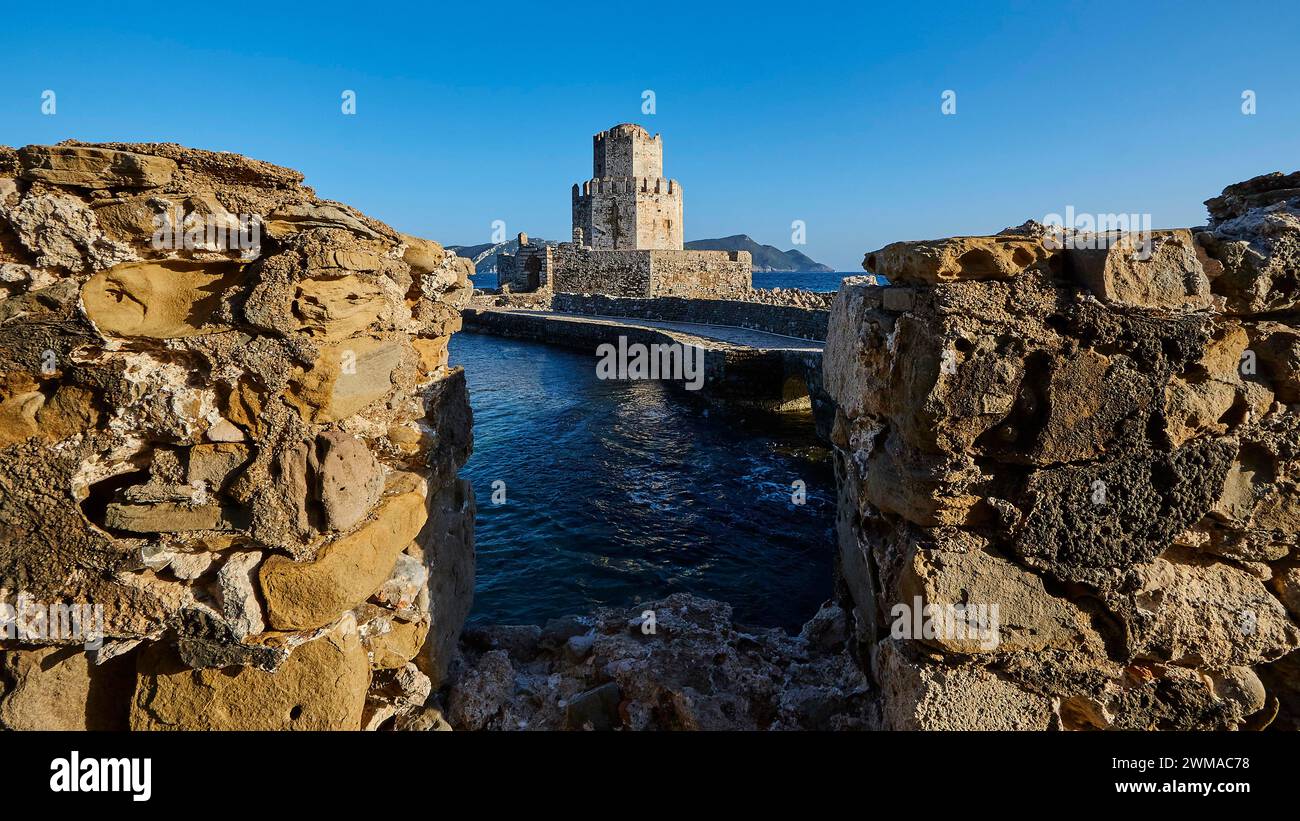 Ammira attraverso un ponte sbriciolato un castello sul mare sotto un cielo blu profondo, torre medievale ottagonale. Isolotto di Bourtzi, fortezza marina di Methoni Foto Stock