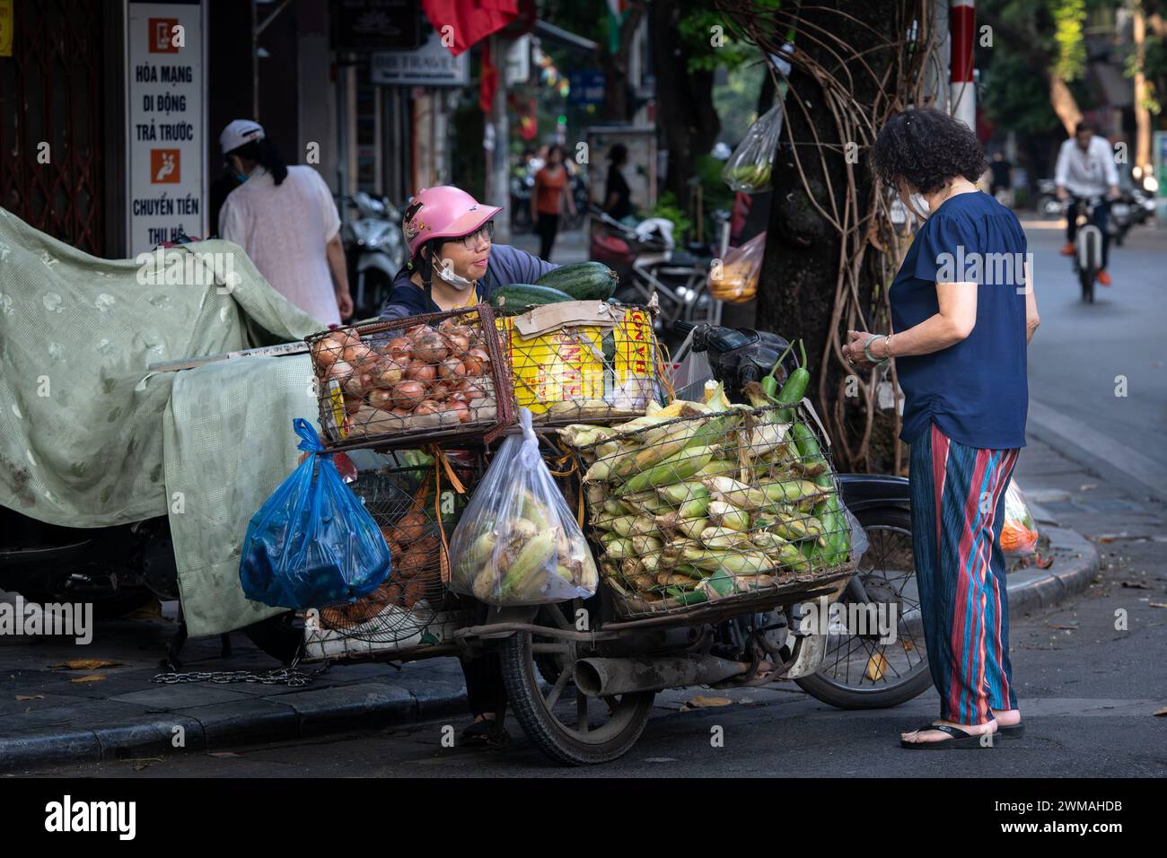 Venditore ambulante che vende cibo nel centro storico di Hanoi, Vietnam Foto Stock