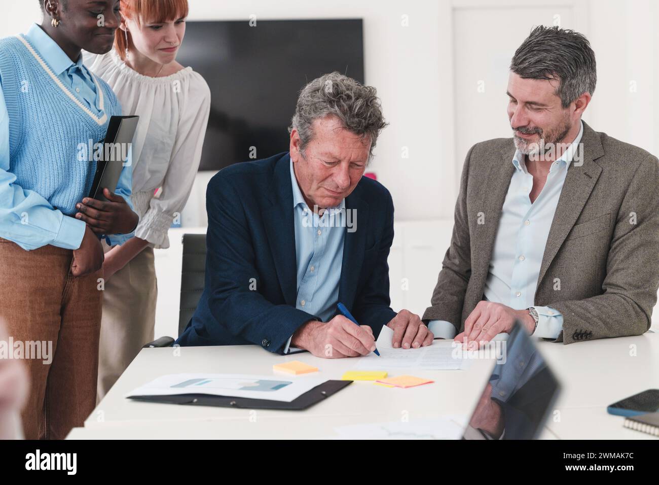 Team aziendale che esamina il contratto - Senior leader firma documento - pianificazione strategica e accordo. Foto Stock