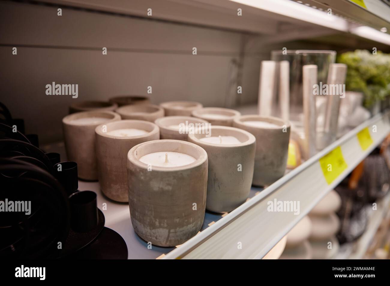 Candele aromatiche profumate nel candelabro in gesso in piedi sul rack in negozio Foto Stock