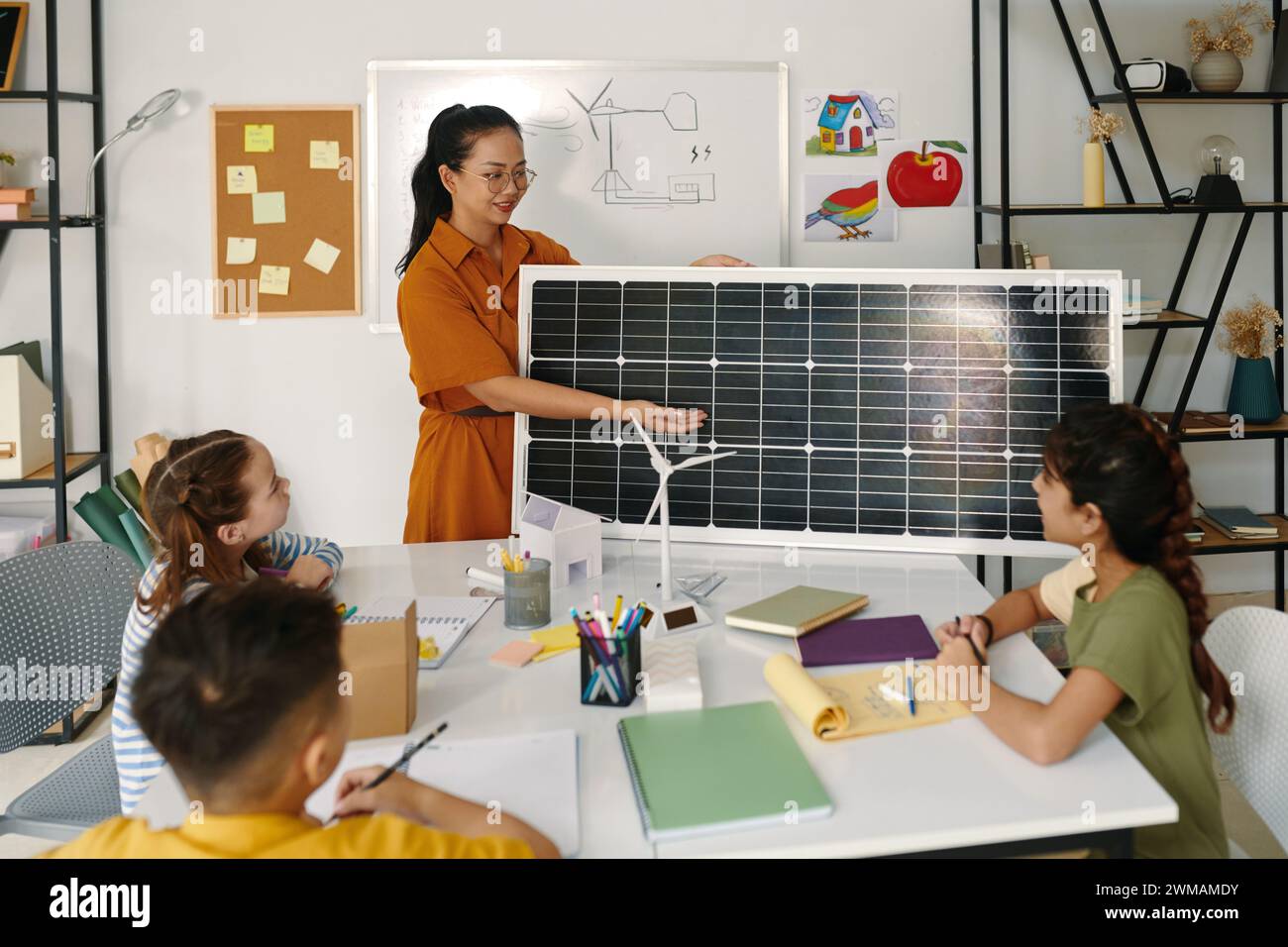 Insegnante positivo che mostra ai bambini il pannello solare e spiega come funziona Foto Stock